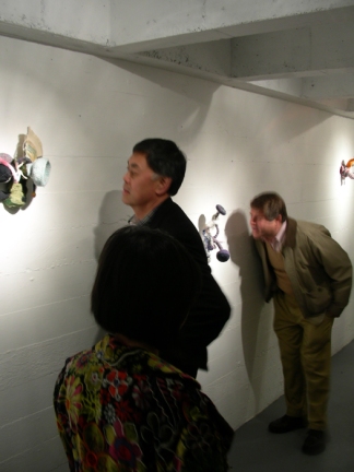 Mark Sprecher in background right, inspecting art.